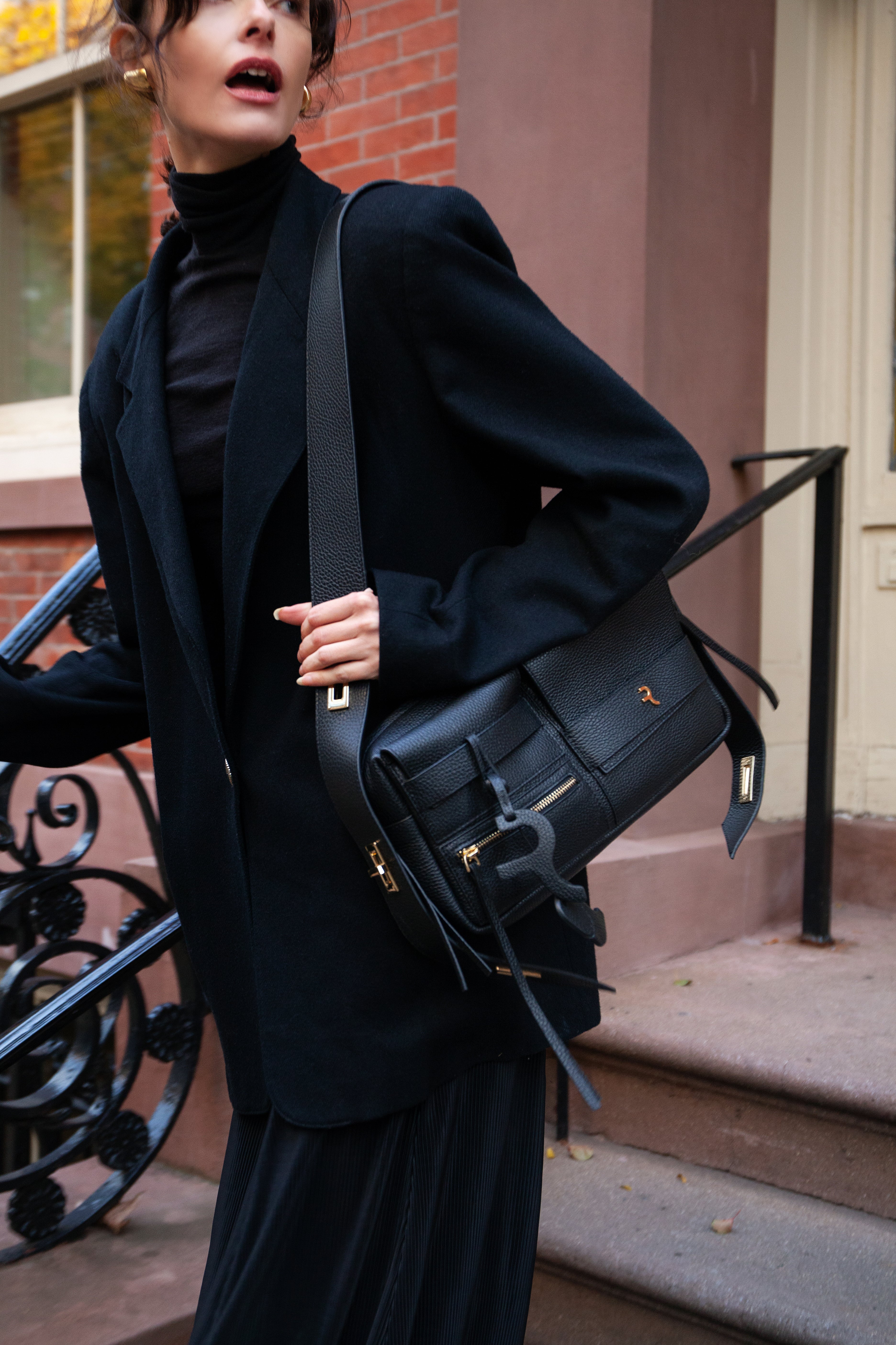 Person holding a black leather bag in an urban setting